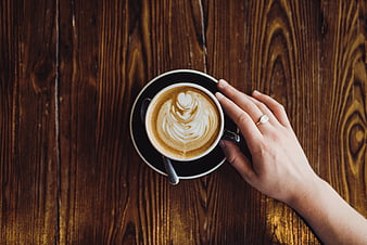 Top View of Woman's Hand Holding Latte Art Coffee Cup