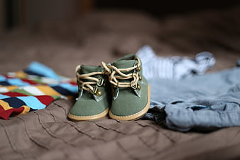 Green Baby Boots with Clothes on Bed