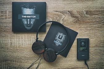 Black headphones and music player on wooden table
