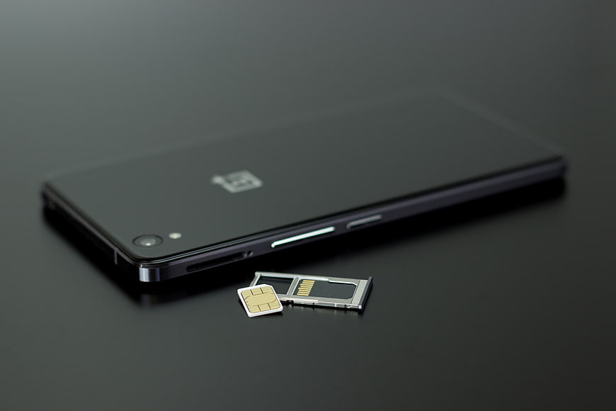 Black smartphone with SIM card tray on dark surface