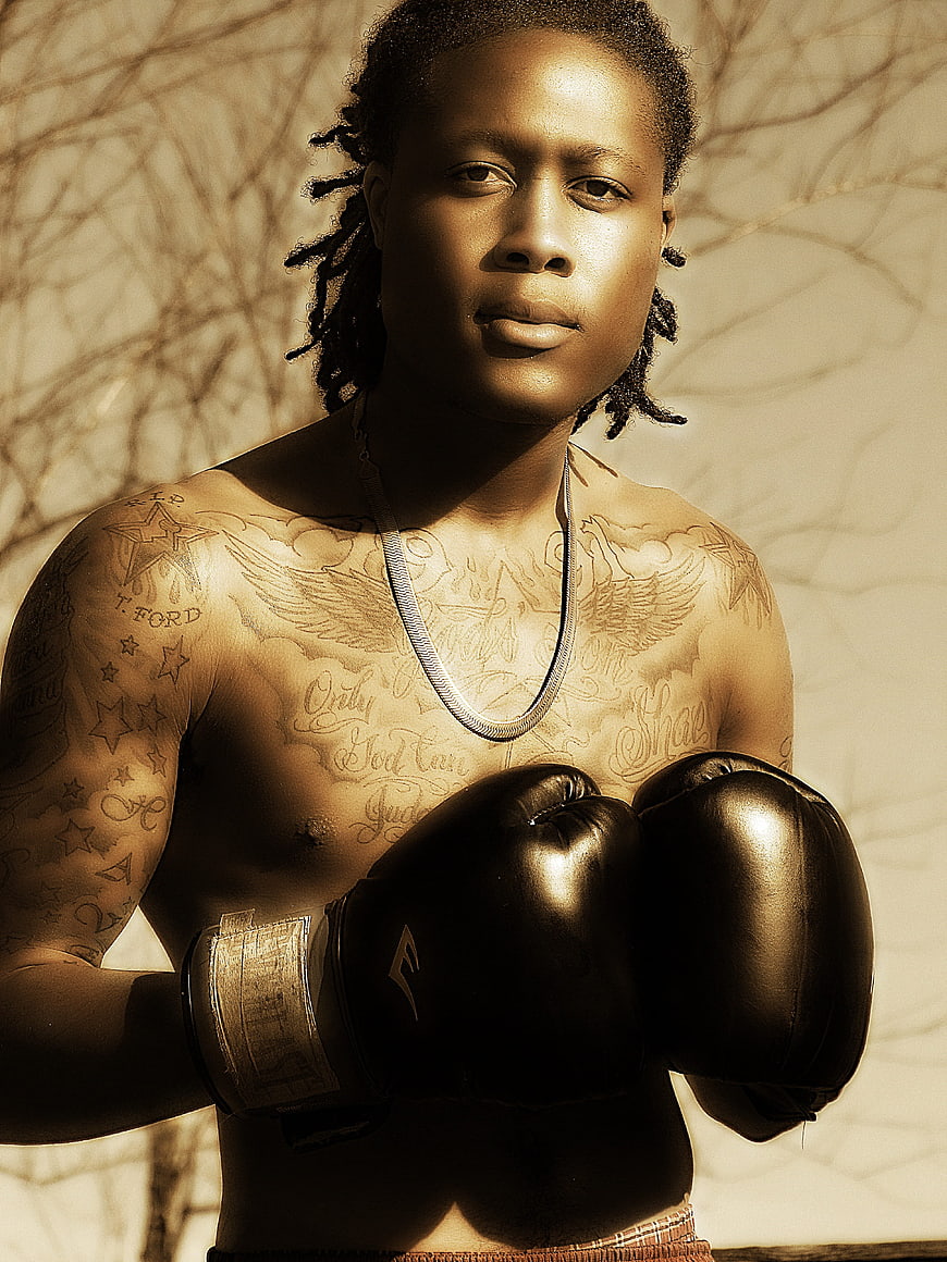 Portrait of tattooed boxer with gloves in sunlight