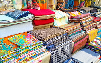 Colorful stacks of patterned textiles at a market stall