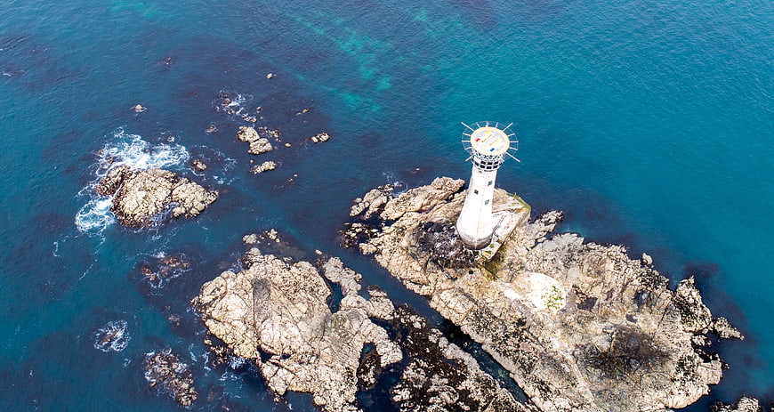 Aerial View of White Lighthouse on Rocky Coast
