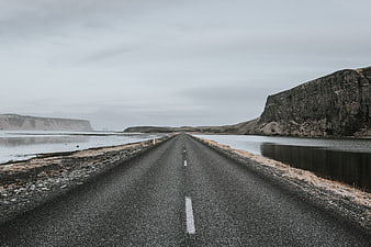 Desolate asphalt road stretching through a misty coastal landscape