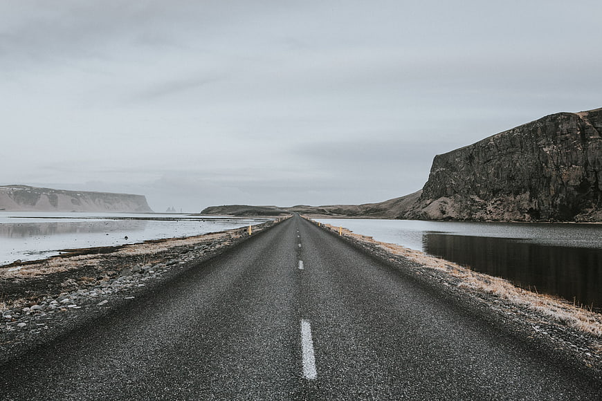 Desolate asphalt road stretching through a misty coastal landscape