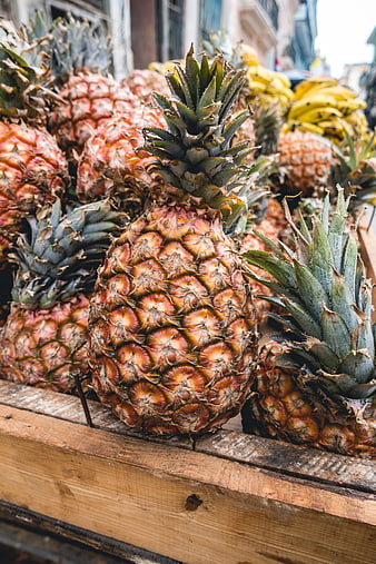 Fresh ripe pineapples in wooden crate at outdoor market