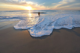 Man Walking in Ocean Waves at Golden Sunset