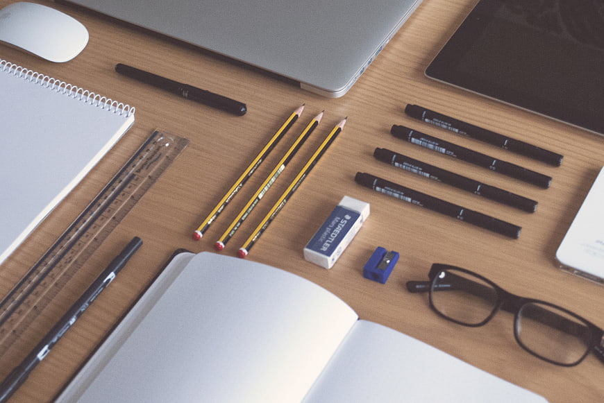 Top-down view of organized workspace with laptop, notebook, and stationery