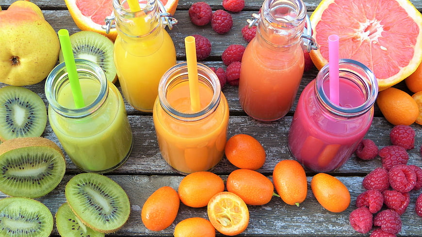 Colorful fruit smoothies with kiwi, raspberry, and grapefruit on wood