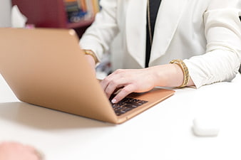 Woman Typing on Gold Laptop in Office