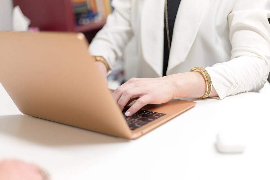 Woman Typing on Gold Laptop in Office