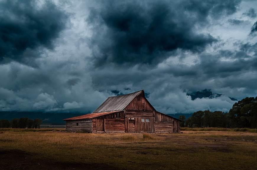 Old wooden barn under dramatic storm clouds in rural landscape
