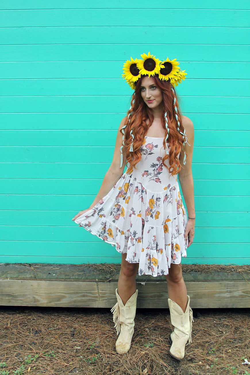 Woman in Floral Dress and Sunflower Crown Against Teal Wall