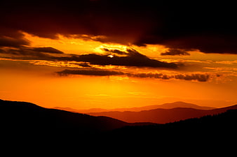 Dramatic Orange Sunset Over Silhouetted Mountain Range Landscape