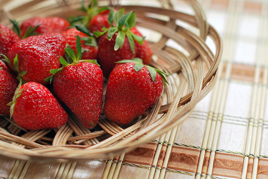 Fresh Red Strawberries in Woven Basket on Bamboo Mat