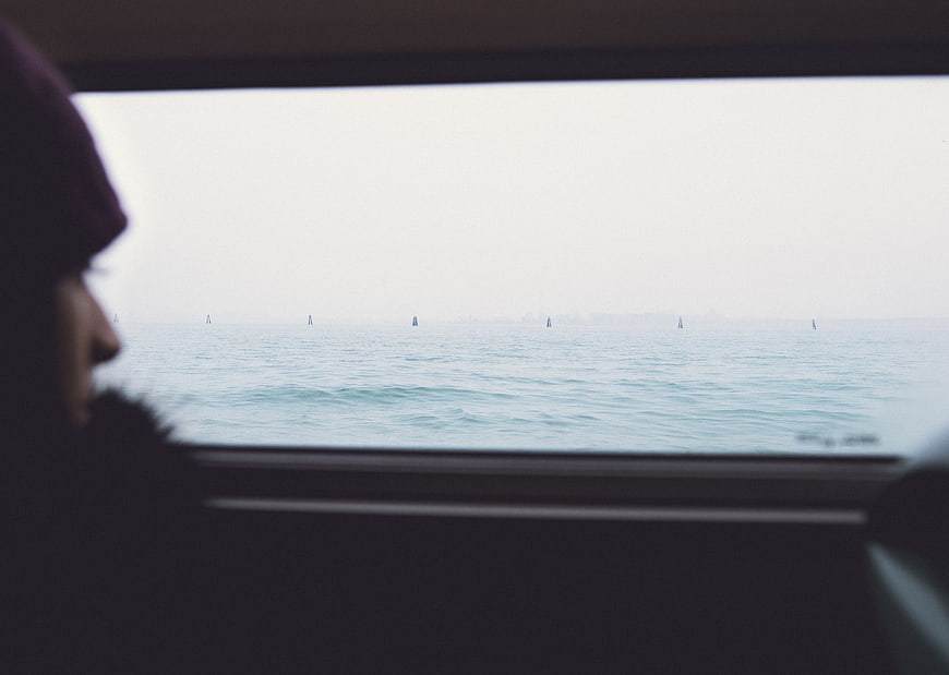 Silhouette of person looking out car window at ocean
