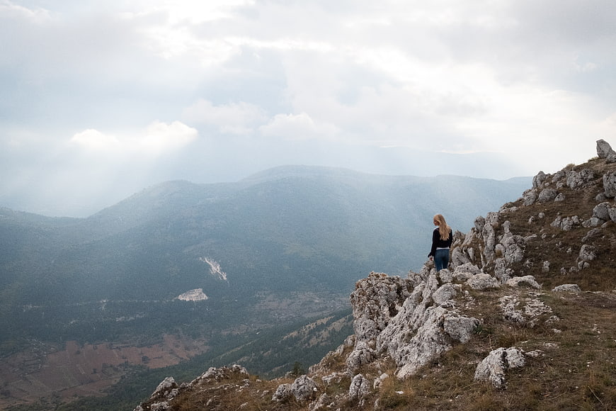 Woman hiking on rocky mountain ridge overlooking valley