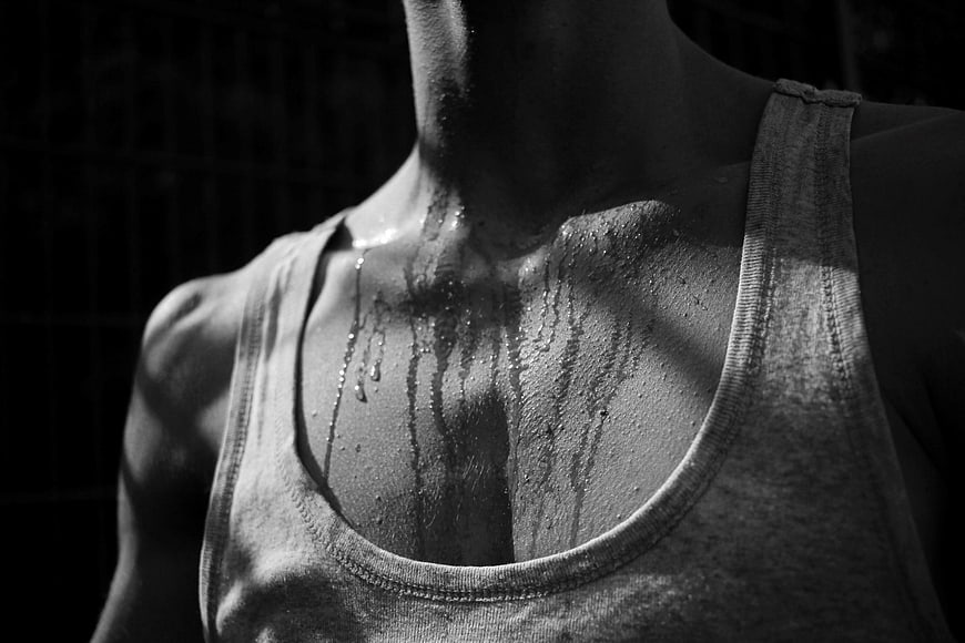 Black and white close-up of a sweaty man's chest and neck