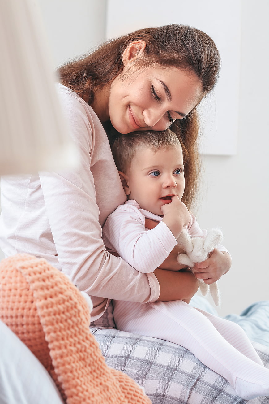 Mother Hugging Baby Girl on Bed