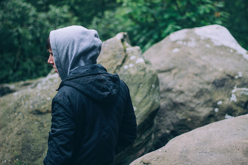 Man in Hoodie Standing on Rocks in Forest