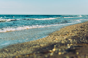 Low angle view of gentle ocean waves on pebble beach