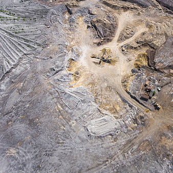 Aerial drone view of open-pit mine excavation site with heavy machinery