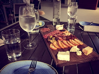 Charcuterie board with cheese, meats, and wine on outdoor table