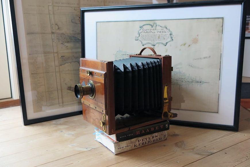 Vintage wooden camera on books with antique maps