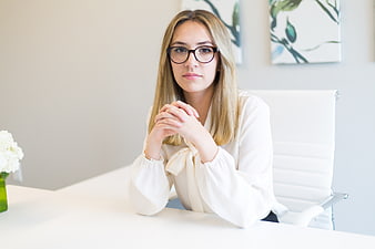 Professional woman with glasses sitting at white office desk