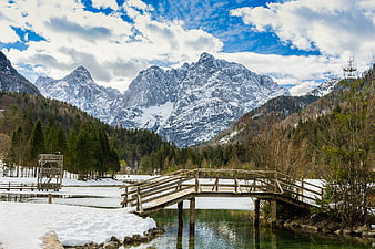 Snowy Alpine Lake with Wooden Bridge and Mountains