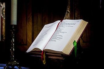 Open Bible on Wooden Stand with Candle in Church