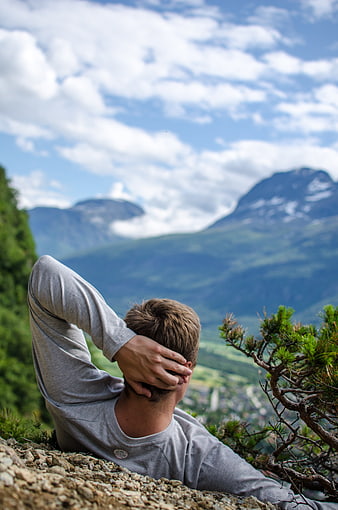 Man relaxing on mountain peak overlooking valley and peaks