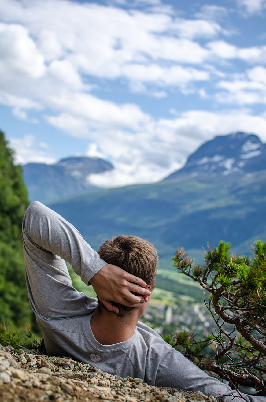 Man relaxing on mountain peak overlooking valley and peaks