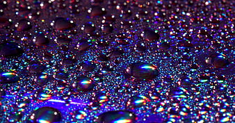 Macro shot of iridescent water droplets on a dark surface