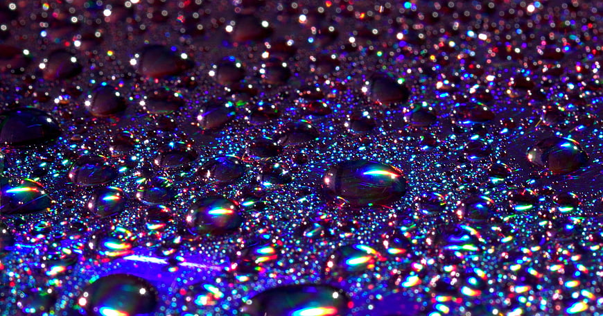 Macro shot of iridescent water droplets on a dark surface