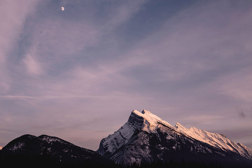 Snow-Capped Mountain Peak at Dusk with Crescent Moon