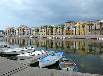Colorful Sardinian harbor with boats and palm trees