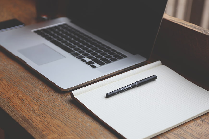 Minimalist workspace with laptop, notebook, and pen on wooden desk