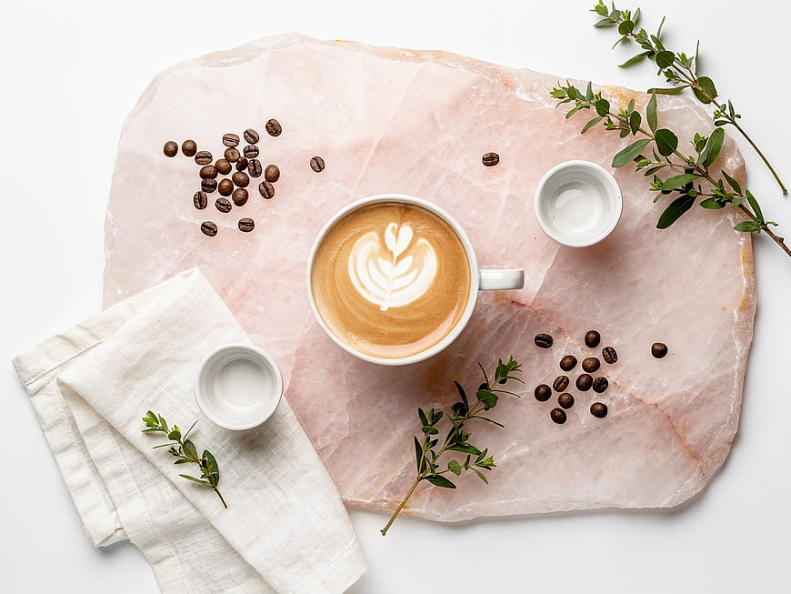 Flat lay latte art on pink stone with coffee beans and herbs