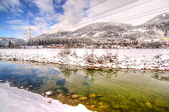 Snowy mountain village reflected in clear winter river stream