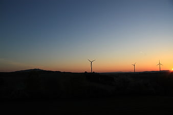 Silhouetted Wind Turbines Against Sunset Sky