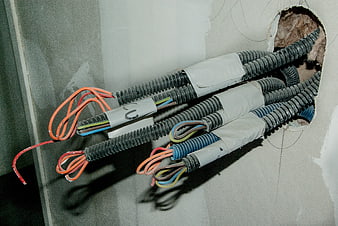 Electrical wiring cables emerging from drywall wall