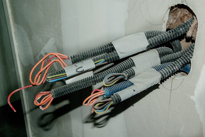 Electrical wiring cables emerging from drywall wall