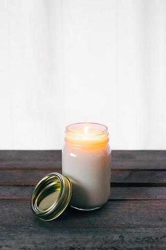 Lit Soy Candle in Mason Jar on Dark Wood Table