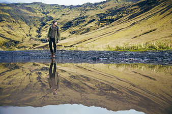 Lone Hiker Standing by Mountain Lake Reflection
