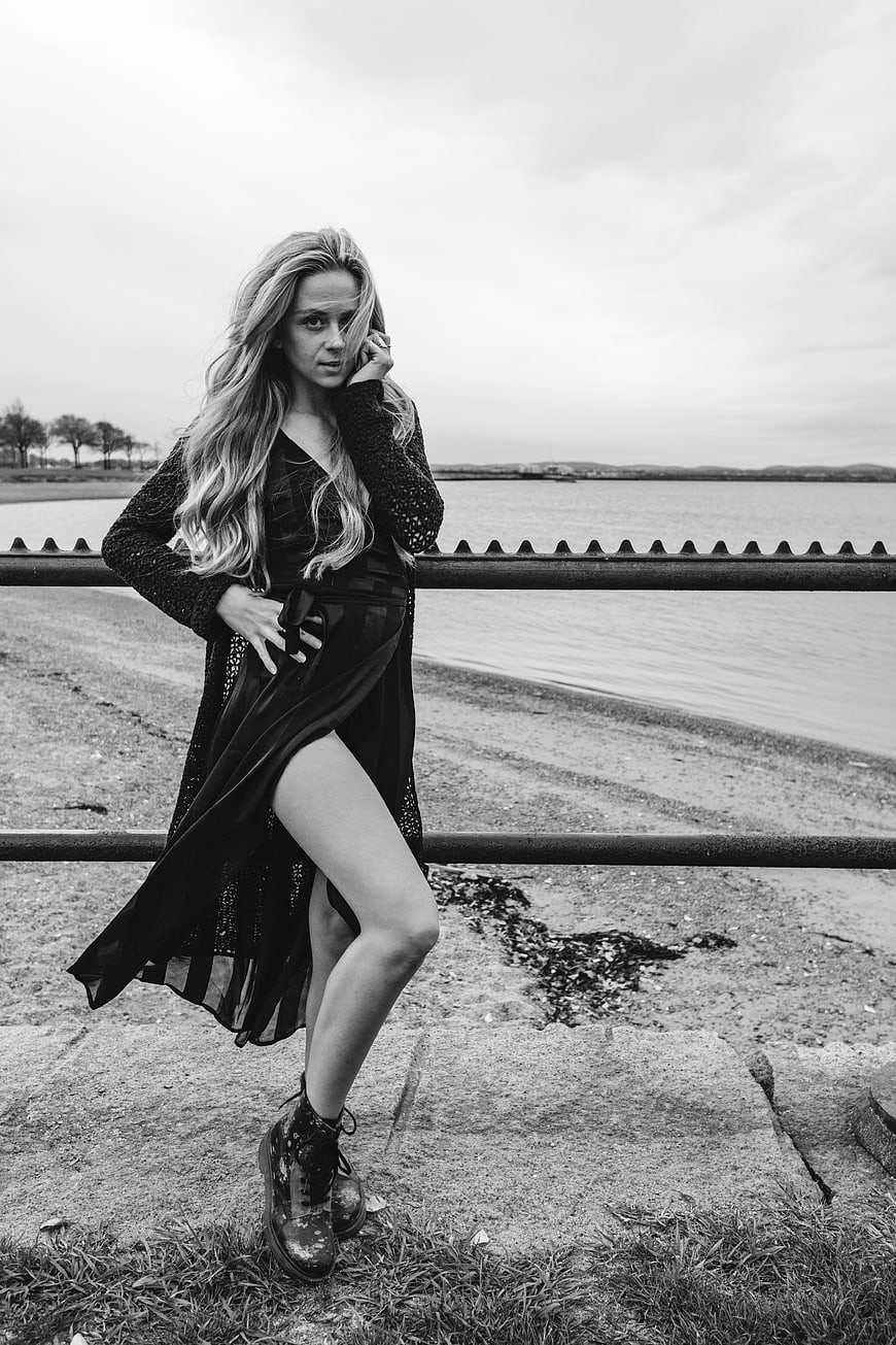 Black and white portrait of stylish woman by the sea