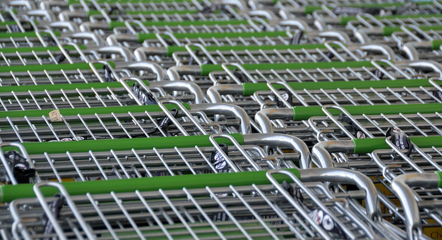 Rows of empty metal shopping carts with green handles in a supermarket