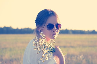 Woman with Sunglasses Holding Daisies in Field