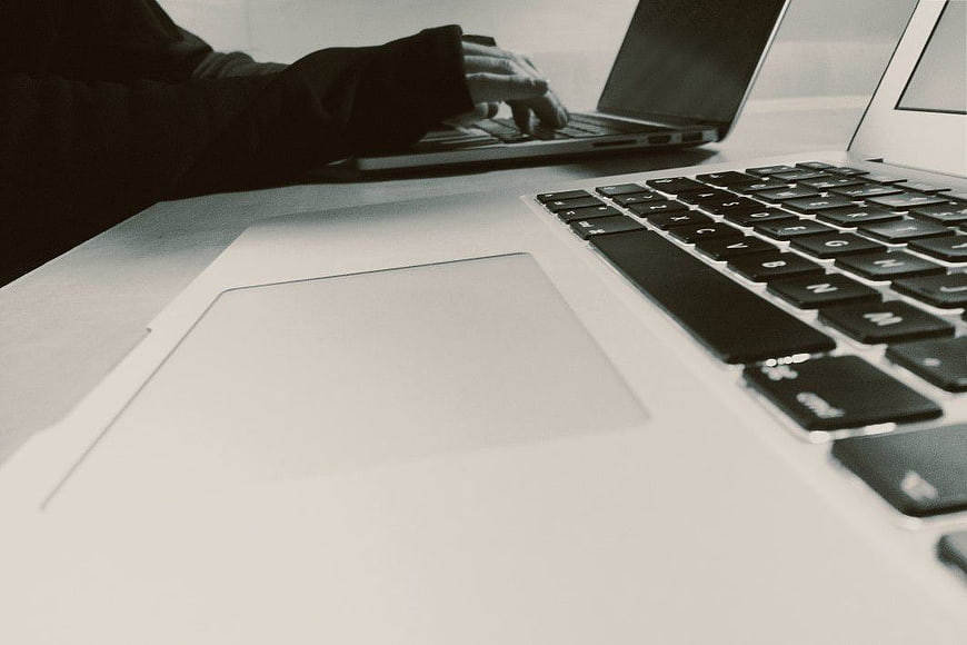 Close-up of hands typing on laptop keyboard in office