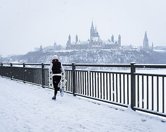 Woman Running on Snowy Path with Parliament Hill Background